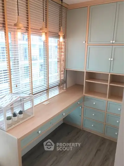 Charming study room with built-in desk and cabinets, featuring stylish pendant lighting and large windows.