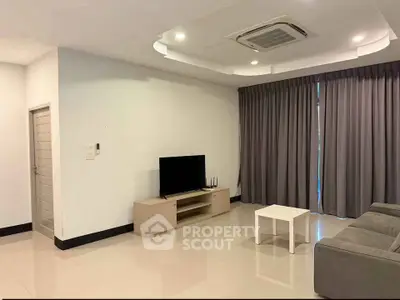 Spacious modern living room with sleek furniture and elegant ceiling design.