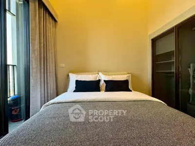 Cozy bedroom with modern decor and large window for natural light.