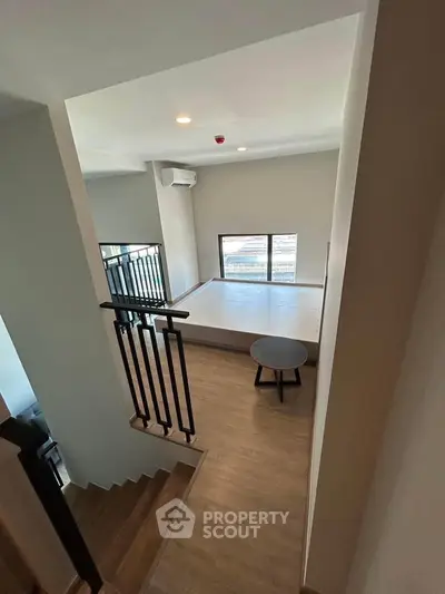 Modern loft-style bedroom with wooden flooring and large window.