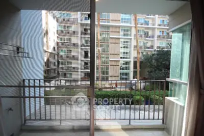 Spacious balcony with a view of modern apartment complex and lush greenery.