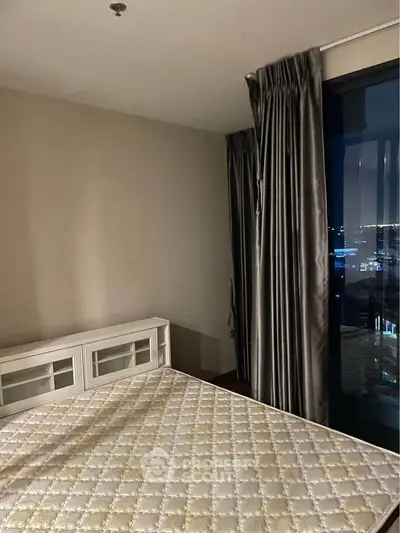 Modern bedroom with large window offering stunning city views, featuring elegant curtains and stylish furniture.