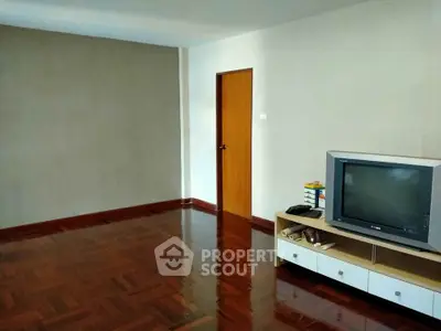 Spacious living room with polished wooden floors and classic TV setup