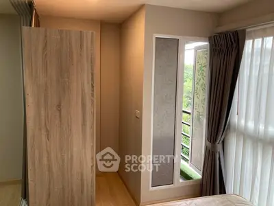 Cozy bedroom with balcony access and natural light, featuring modern wooden wardrobe and elegant curtains.
