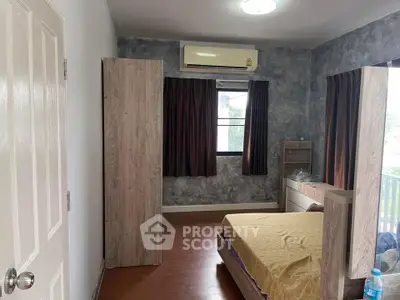 Cozy bedroom with modern decor and air conditioning, featuring a large window for natural light.