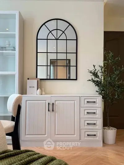 Stylish living room with elegant cabinet, arched mirror, and cozy decor accents.