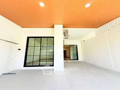 Spacious modern patio with sleek glass doors and warm wooden ceiling, perfect for outdoor relaxation.