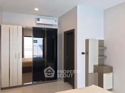 Modern bedroom with sleek wardrobe and air conditioning in a stylish apartment.