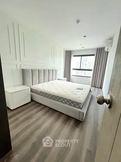 Spacious bedroom with modern decor and large window for natural light.