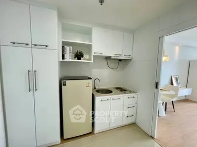 Modern compact kitchen with white cabinets and small fridge in a cozy apartment