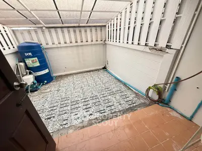 Spacious outdoor utility area with water tank and tiled flooring, ideal for storage or laundry setup.