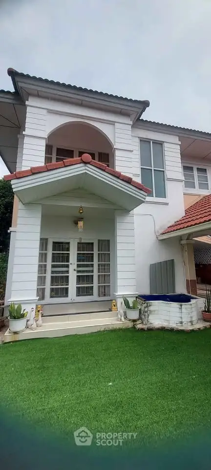 Charming two-story house with lush green lawn and elegant entrance