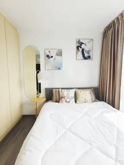 Cozy bedroom with modern decor and ample natural light, featuring stylish artwork and elegant furnishings.