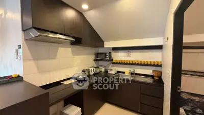 Modern kitchen with sleek dark cabinets and built-in appliances, featuring a compact and efficient layout.