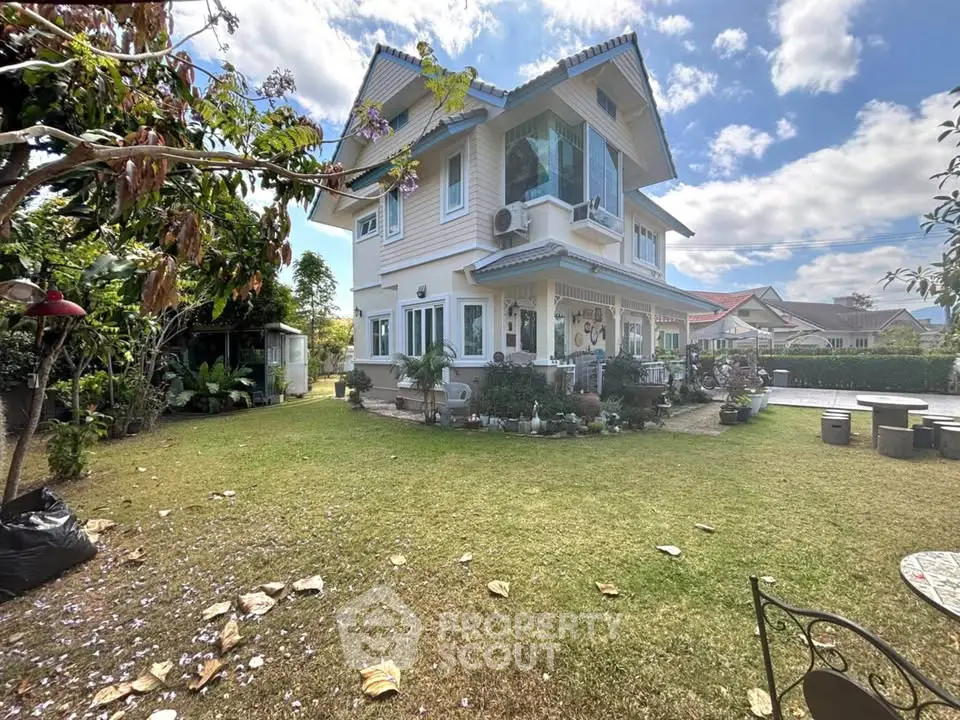 Charming two-story house with lush garden and spacious lawn under a clear blue sky.