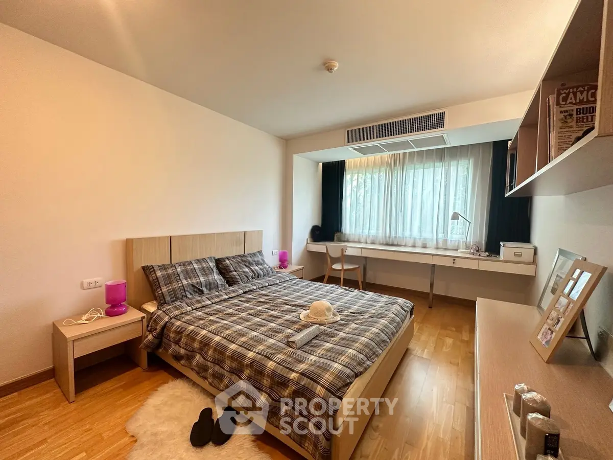 Spacious bedroom with modern decor and natural light, featuring a cozy bed and stylish workspace.