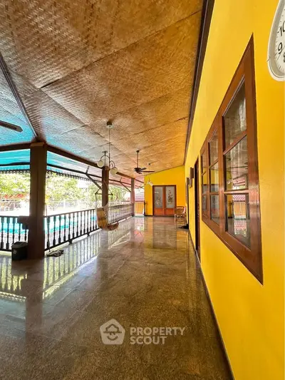 Spacious outdoor patio with vibrant yellow walls and pool view, perfect for relaxation and entertainment.