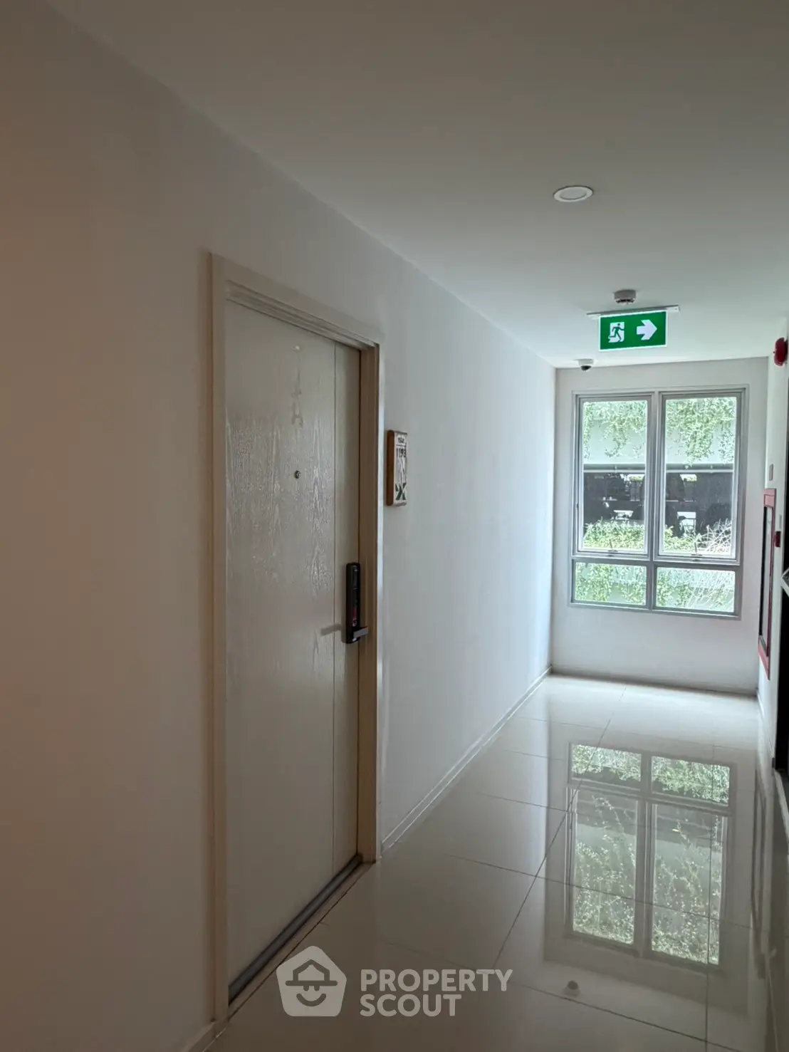 Modern apartment corridor with glossy floors and emergency exit sign