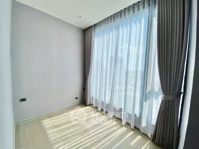 Bright and airy room with large window and elegant curtains, perfect for a cozy living space.