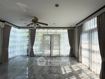 Spacious living room with marble flooring and large windows for natural light.
