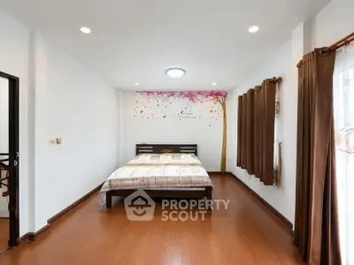 Spacious bedroom with elegant wooden flooring and artistic wall decor