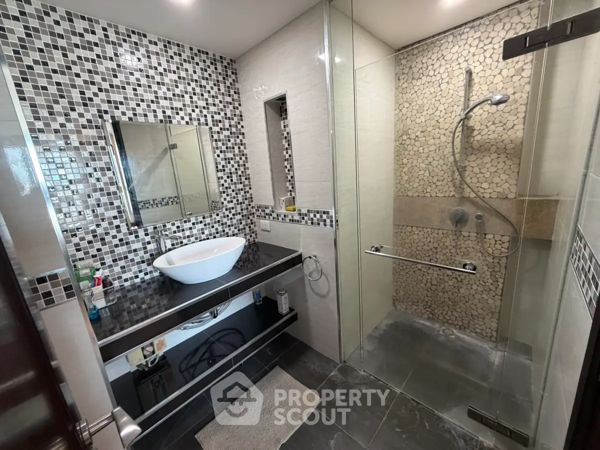 Modern bathroom with stylish mosaic tiles and glass shower enclosure