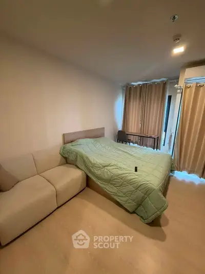 Cozy bedroom with modern decor, featuring a comfortable bed, sofa, and natural light from large windows.
