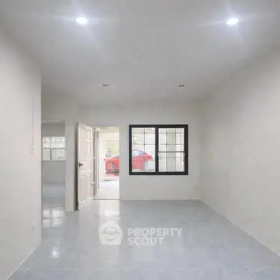 Spacious empty room with tiled flooring and large window, ideal for customization.