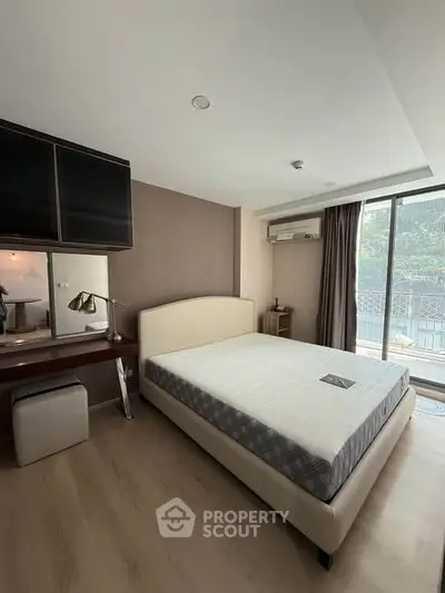 Spacious bedroom with modern decor and large window offering natural light and outdoor view.