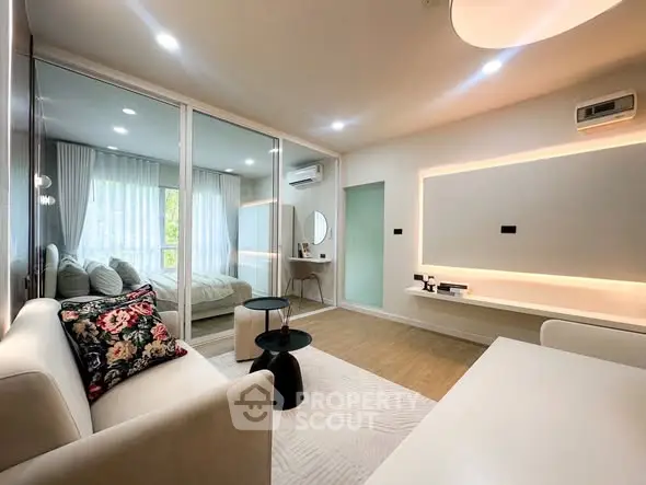 Modern living room with elegant decor and glass partition leading to a cozy bedroom.