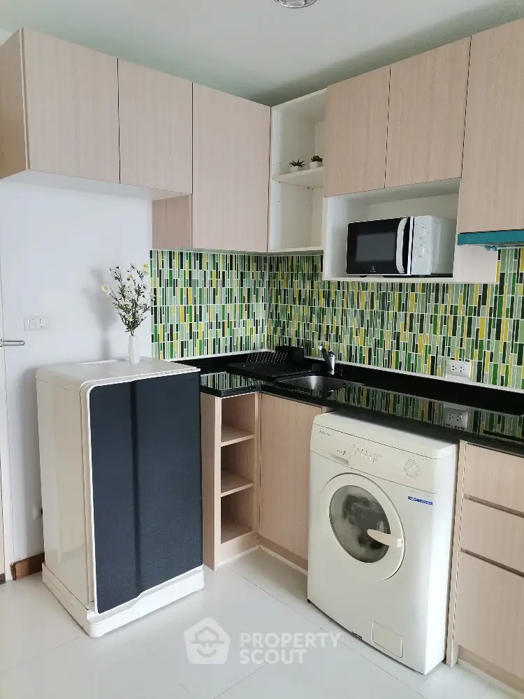 Modern kitchen with washing machine and microwave, stylish backsplash, sleek cabinets, and ample storage space.