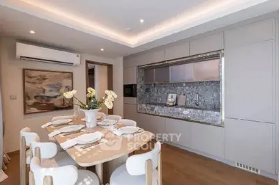 Elegant dining area with modern kitchen featuring sleek cabinetry and stylish decor.