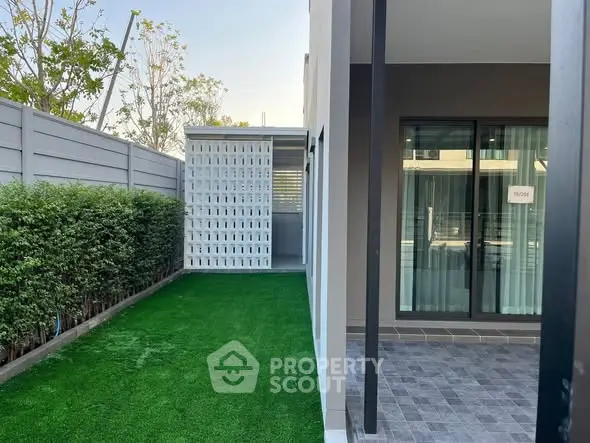 Modern townhouse exterior with lush green lawn and stylish patio area.