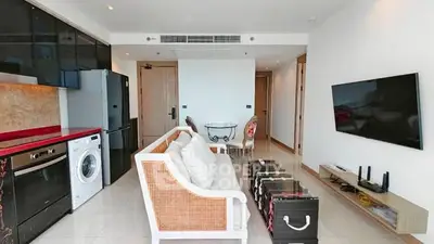 Modern living room with stylish furniture, wall-mounted TV, and integrated kitchen appliances.