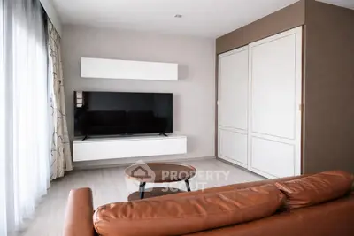 Modern living room with sleek TV setup and stylish brown leather sofa.