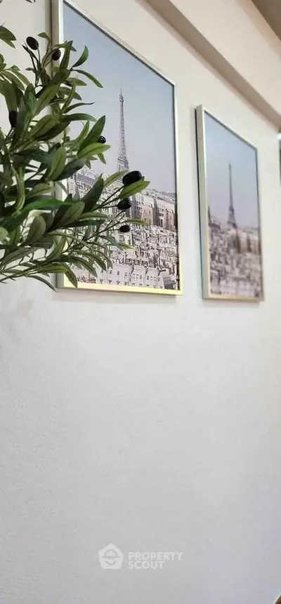 Stylish interior wall with framed art and decorative plant, perfect for modern living spaces.