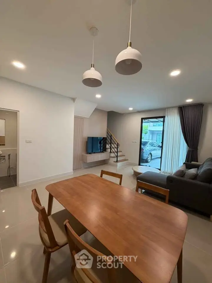 Modern living room with dining area, stylish furniture, and natural light from large windows.
