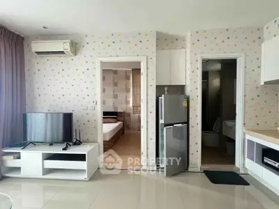 Modern apartment interior with TV, fridge, and bedroom view