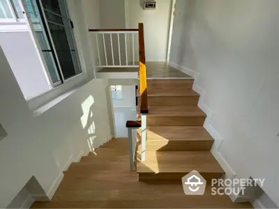 Modern staircase with wooden steps and white railing in a bright home interior