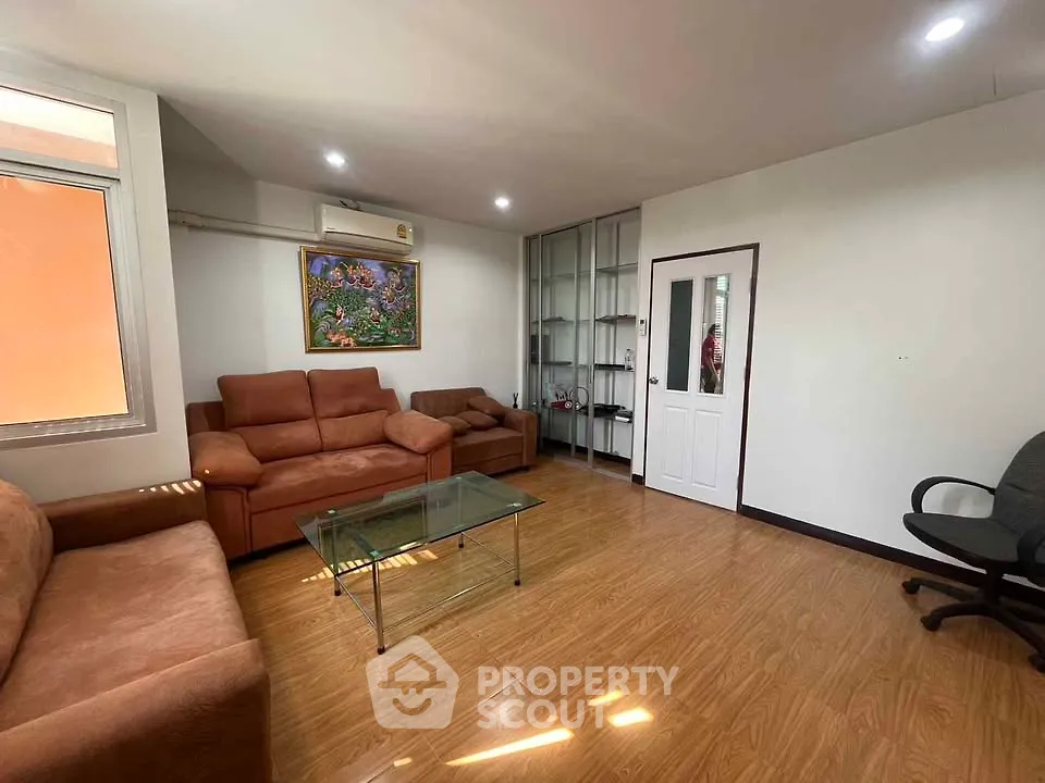 Spacious living room with modern furniture and wooden flooring, perfect for relaxation and entertainment.