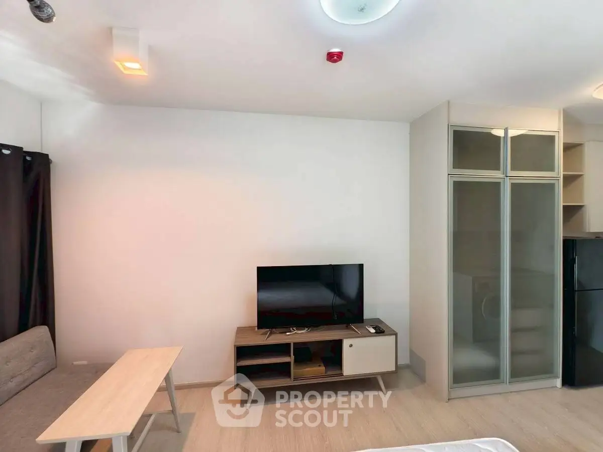 Modern living room with TV, sofa, and glass cabinets in a cozy apartment.