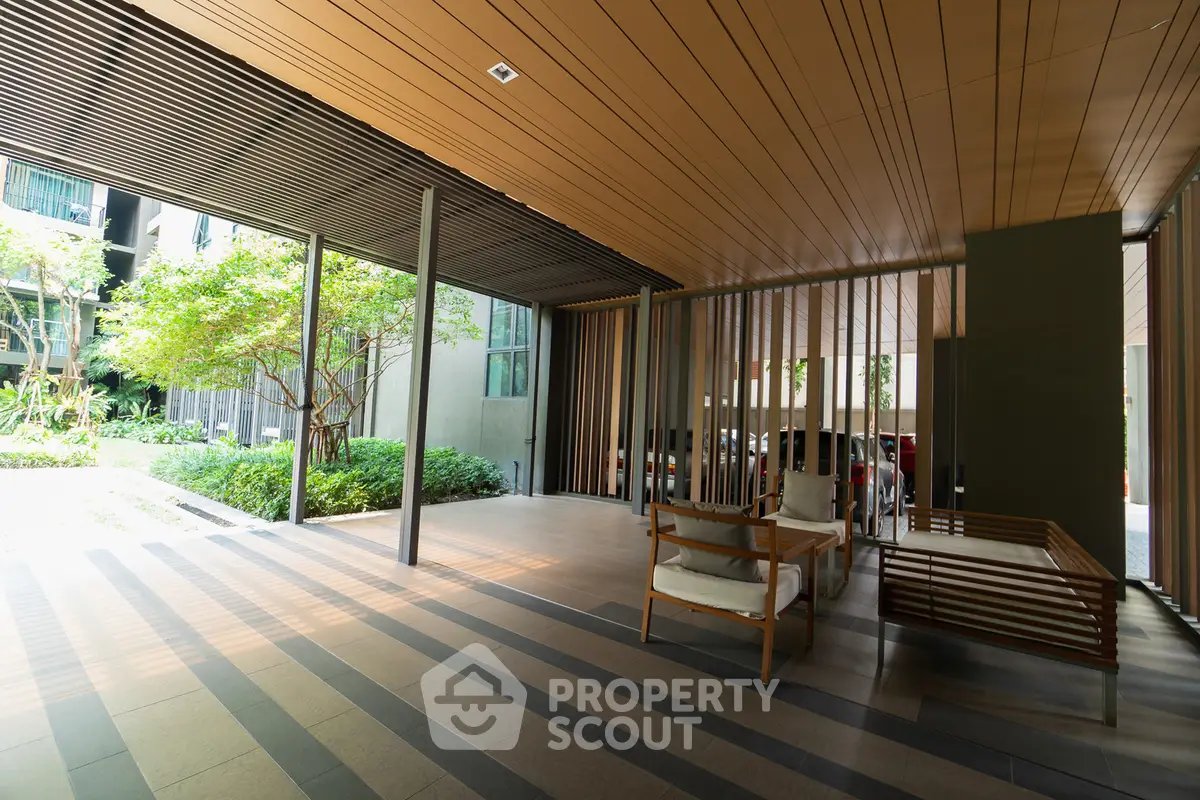 Modern building entrance with stylish seating and lush greenery, perfect for relaxation and welcoming guests.