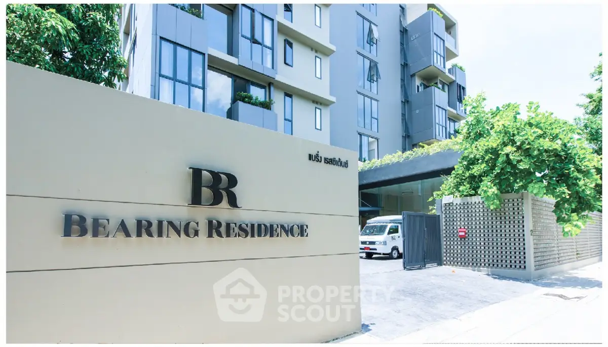 Modern apartment building entrance with lush greenery and sleek design.
