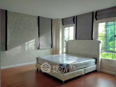 Spacious bedroom with large windows and elegant bed frame in a modern home.