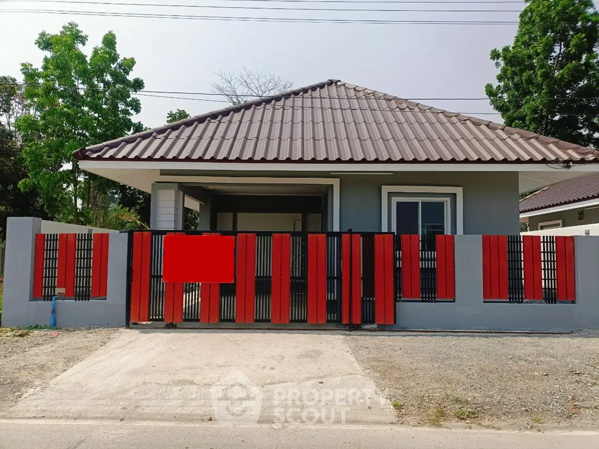 Charming single-story house with modern red and black gate, perfect for cozy living.