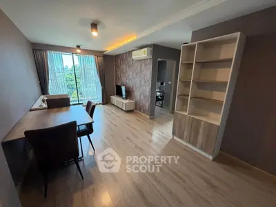 Spacious modern living room with wooden flooring and large windows offering a serene view.