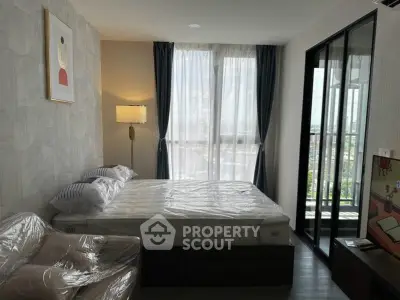 Modern bedroom with large window and balcony access in a stylish apartment.