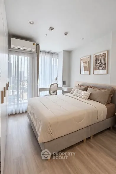 Modern bedroom with cozy decor and large windows offering city views.