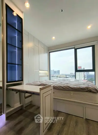Modern bedroom with large window offering city view and sleek built-in storage solutions.