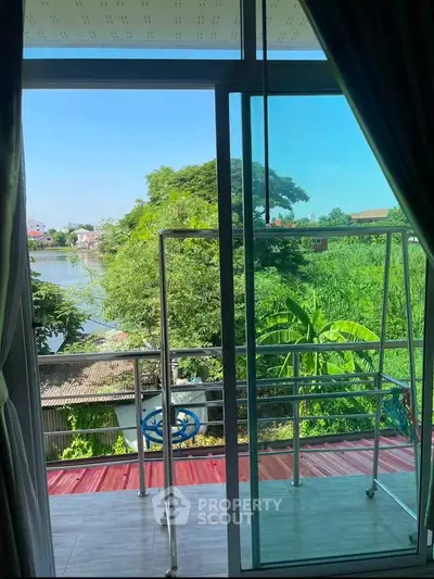 Charming balcony view with lush greenery and serene waterway, perfect for relaxation and tranquility.